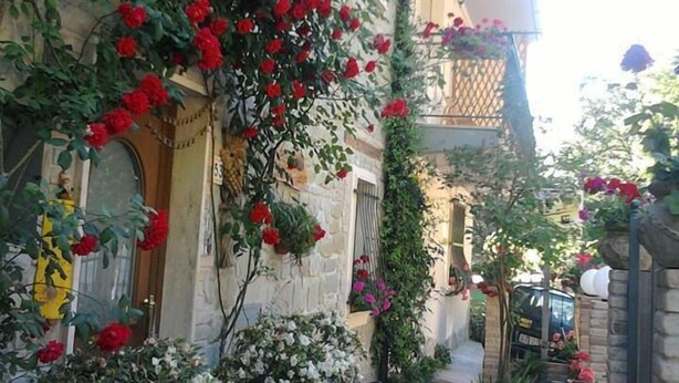 A stone building with red and white flowers in pots and hanging vines. - B&B Villa Filetta (Roccafluvione)