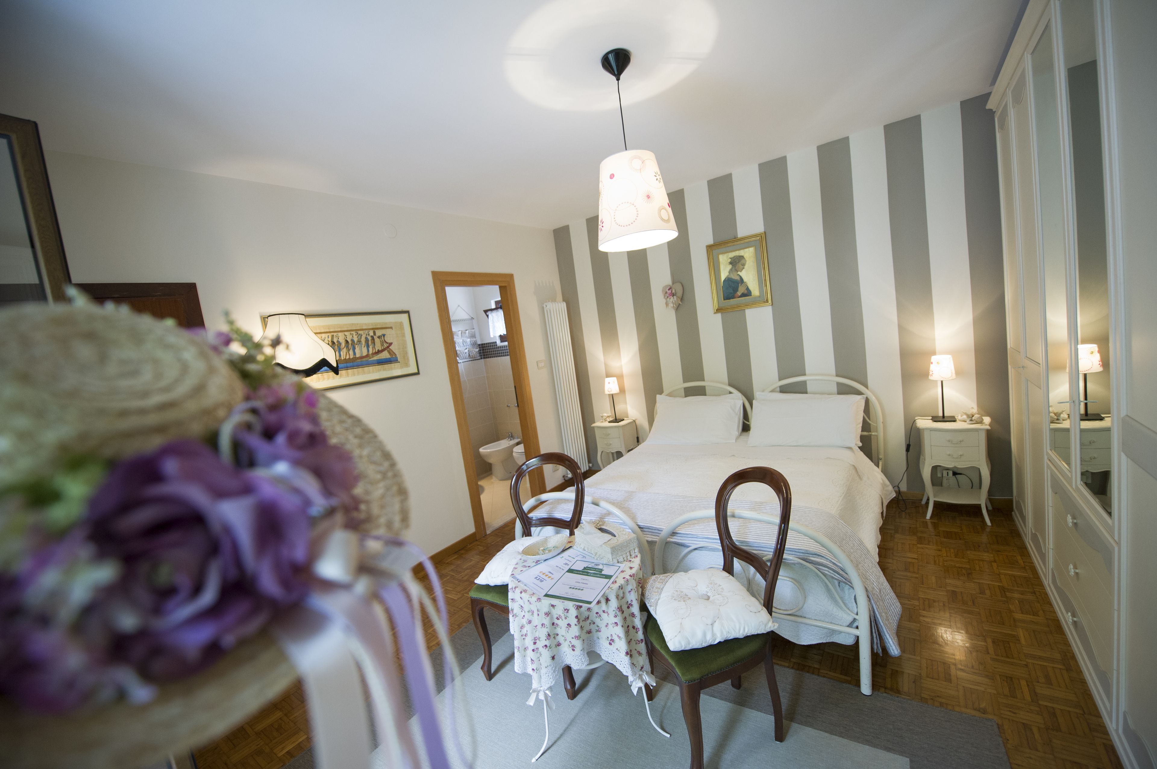 A bedroom with a bed, bedside tables, a mirror, and a hanging light fixture.