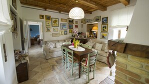 A dining area with a wooden table and chairs, surrounded by a brick fireplace and a wall adorned with framed pictures. - B&B Villa Filetta (Roccafluvione)