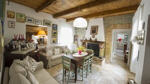 A cozy living room with a wooden ceiling, a fireplace, and a dining area with a table and chairs. - B&B Villa Filetta (Roccafluvione)