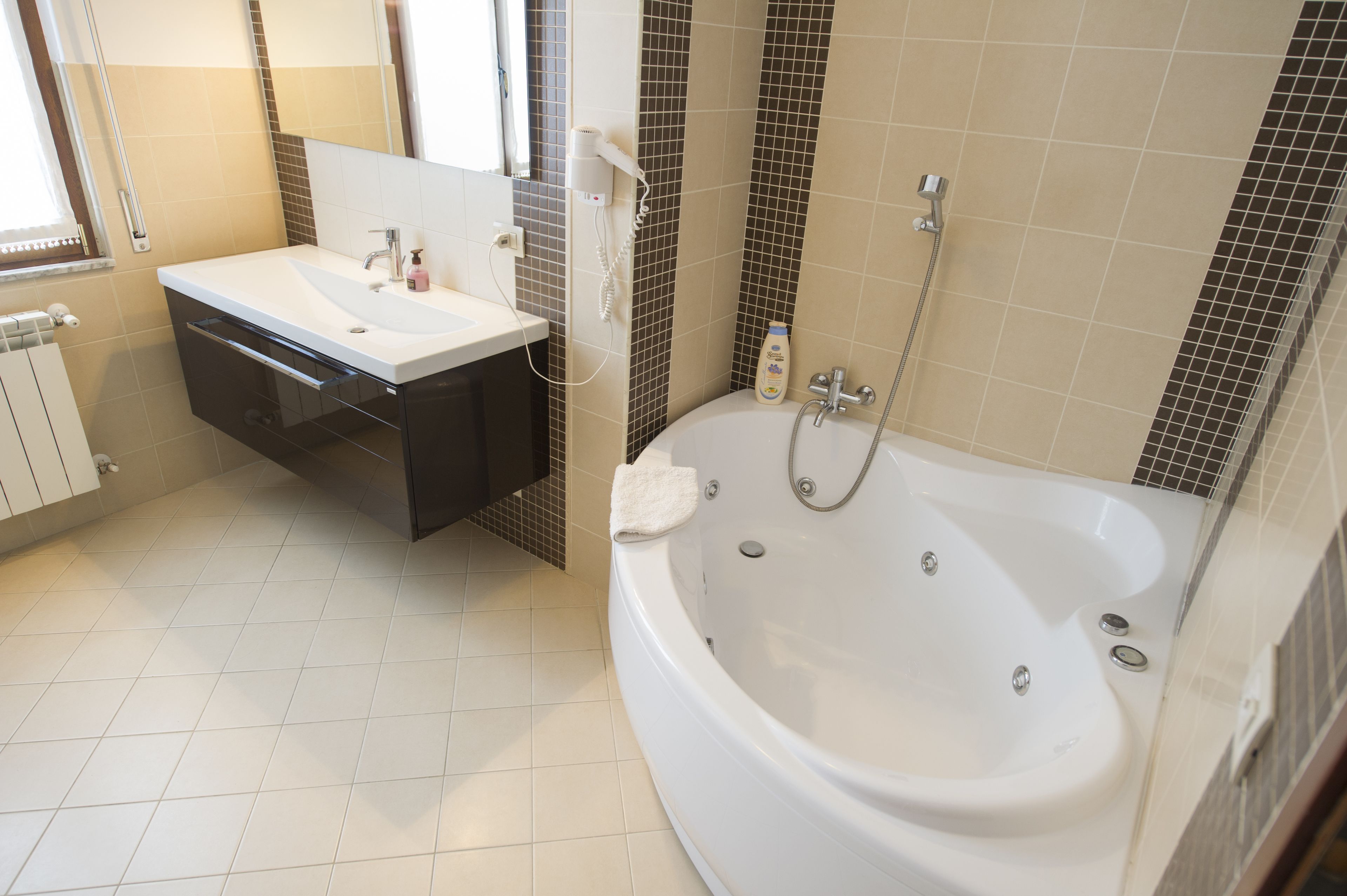 Ein modernes Badezimmer mit einem weißen Waschbecken, einem dunklen Schrank und einer großen Badewanne.