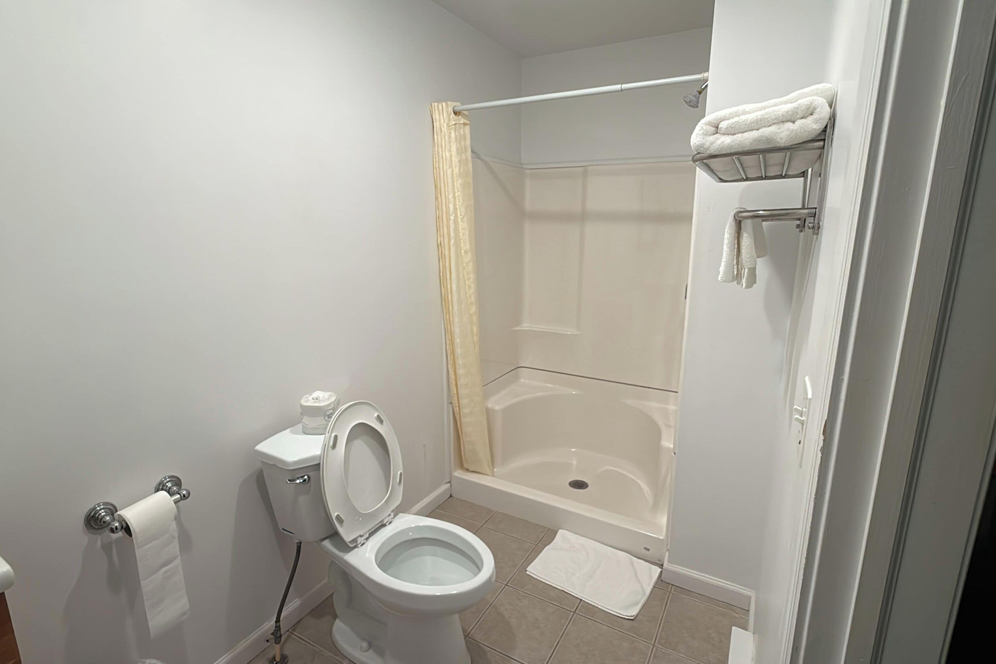 A bathroom with a toilet, a shower with a glass door, and a towel rack.
