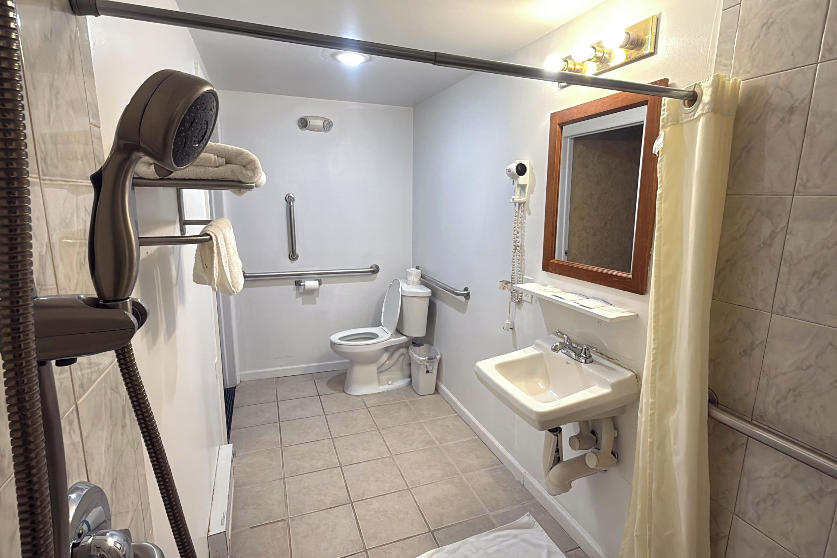 Un baño con ducha, inodoro, lavamanos y secador de pelo.