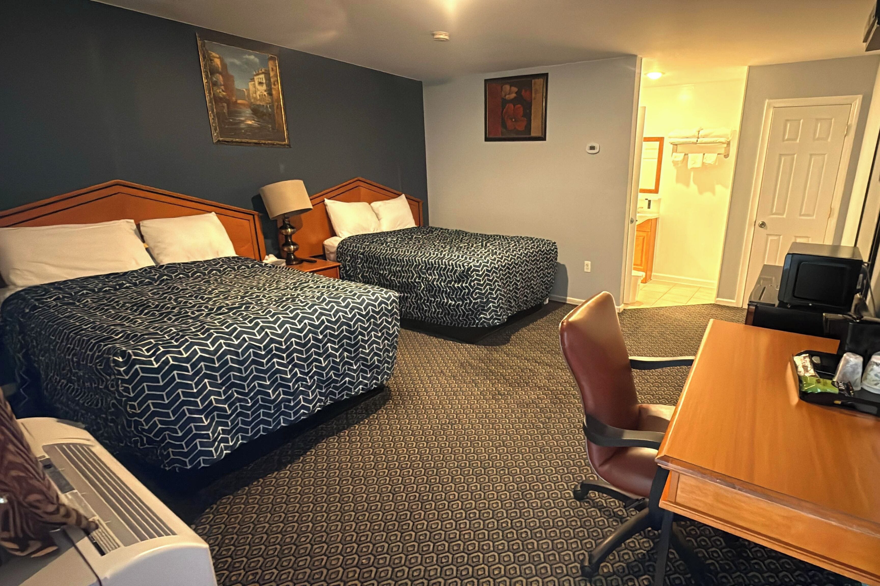 Une chambre d’hôtel avec deux lits, un bureau, une chaise et une télévision.