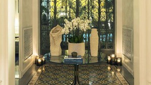 A grand entrance with a decorative iron gate, a chandelier, and a table with flowers and candles. - Palazzo Dama (Rome)