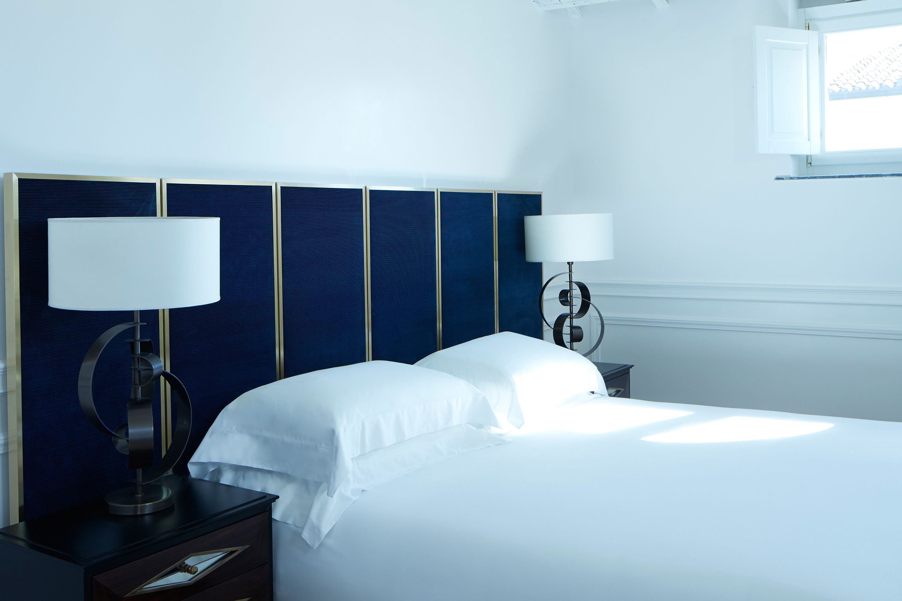 A hotel room with a large bed, two bedside tables, and a window.
