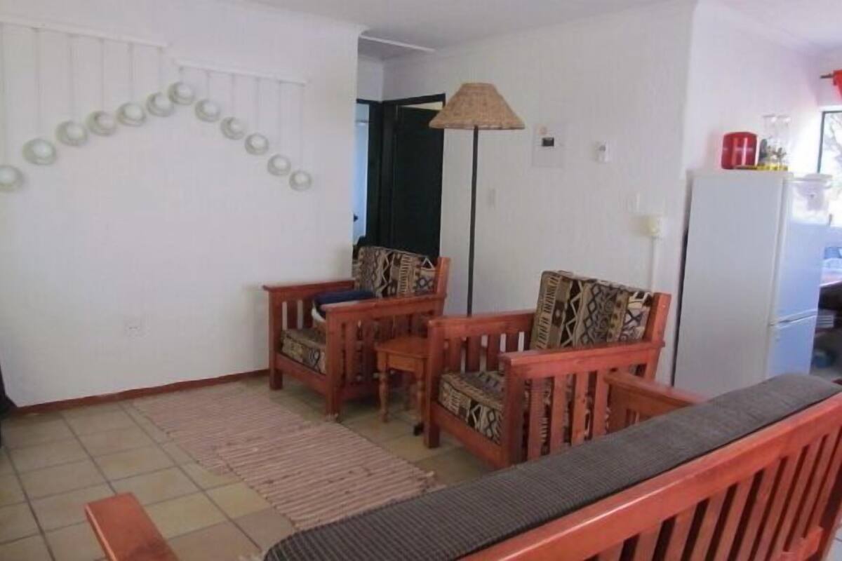 A living room with a sofa, two chairs, a patterned rug, and a wall-mounted circular decoration.