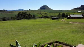 A rural landscape with a large open field, a few scattered trees, and a prominent hill in the background. - Pumula Guest Farm (Fouriesburg)