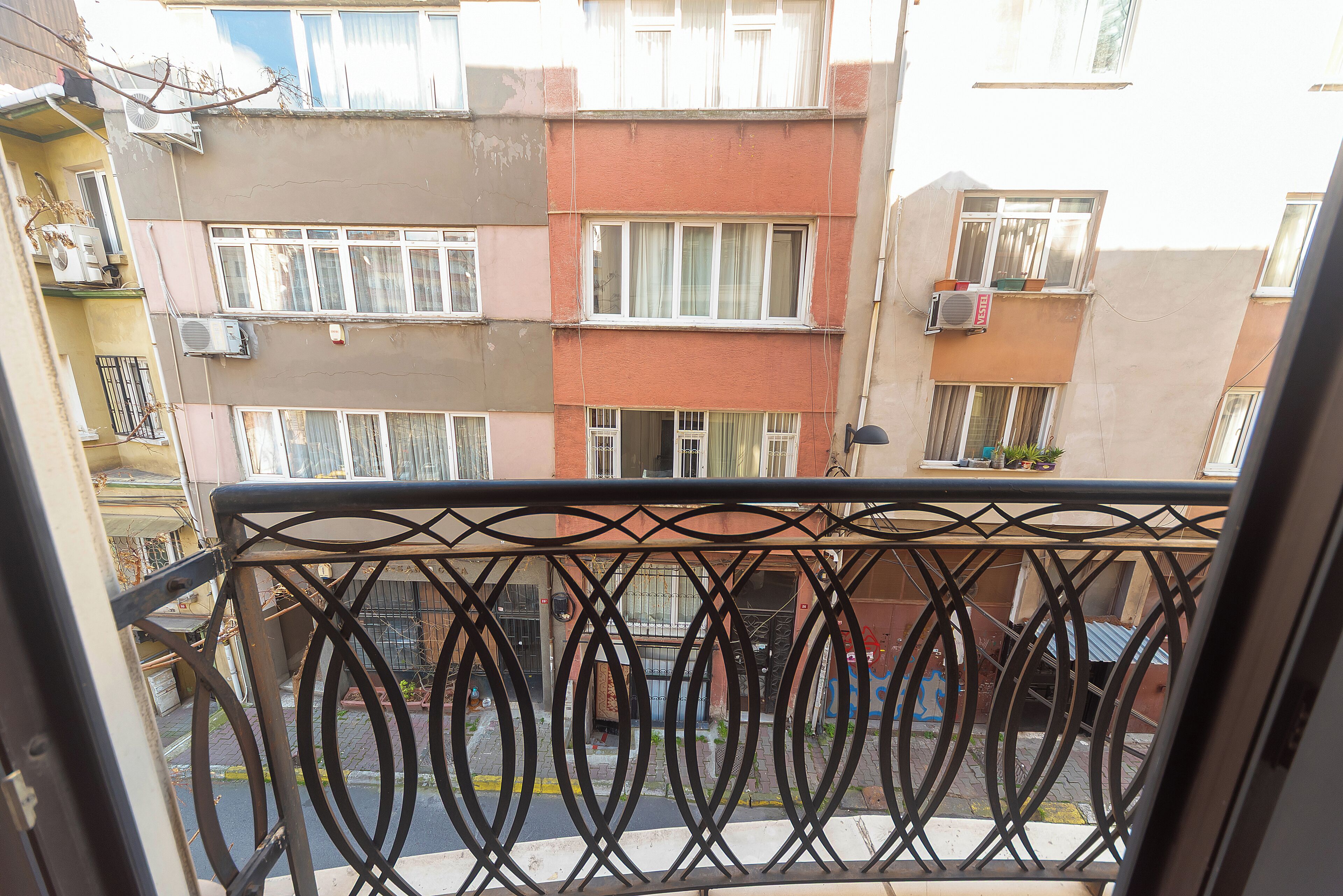 A multi-story residential building with balconies, air conditioning units, and a street view.