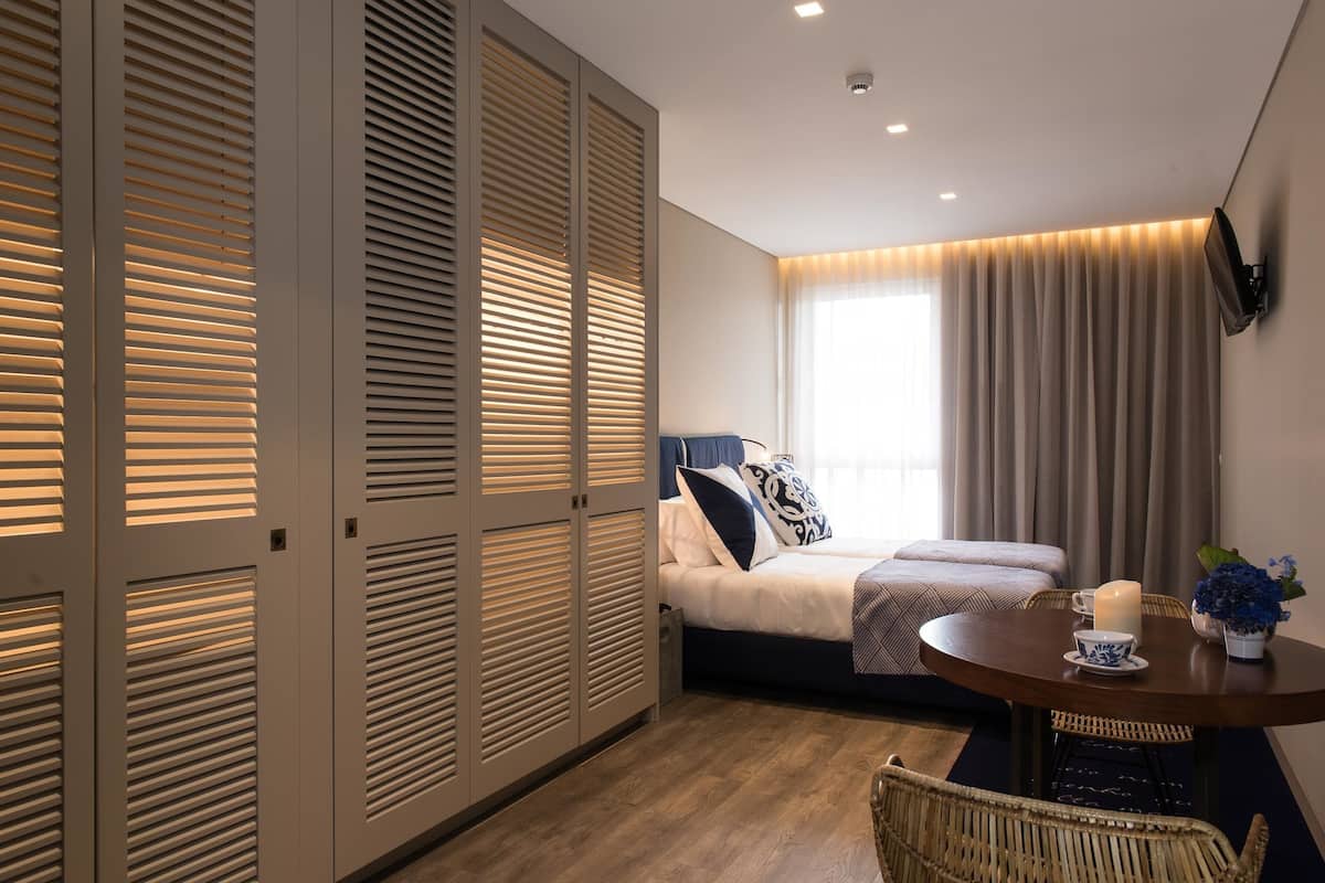 A modern bedroom with a bed, bedside table, and a view of the outdoors.