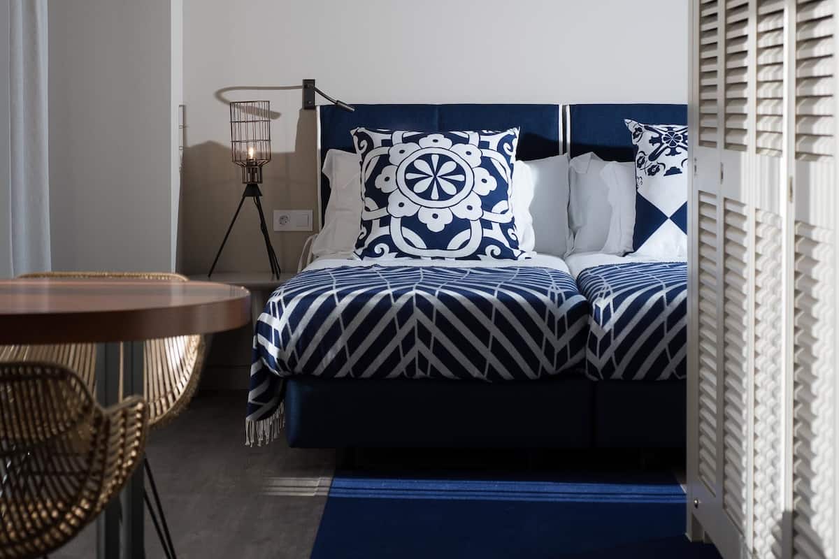 A modern bedroom with a bed, a bedside table, a lamp, and a chair.