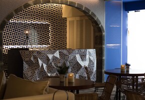 Un comedor con pared decorativa, una mesa redonda con velas y sillas de mimbre.