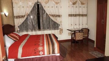 A bedroom with a bed, a small table with chairs, and a wardrobe.