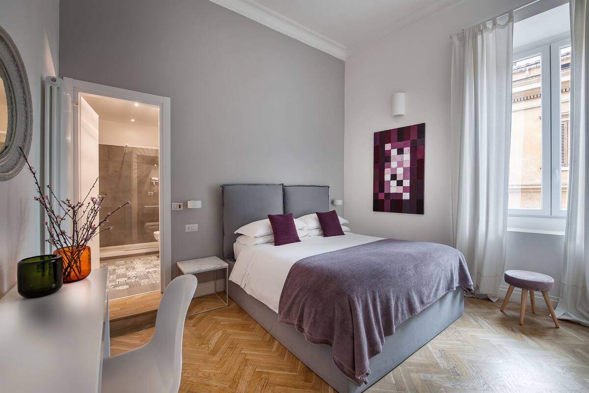 Un dormitorio moderno con una cama grande, una mesita de noche y una ventana con cortinas.