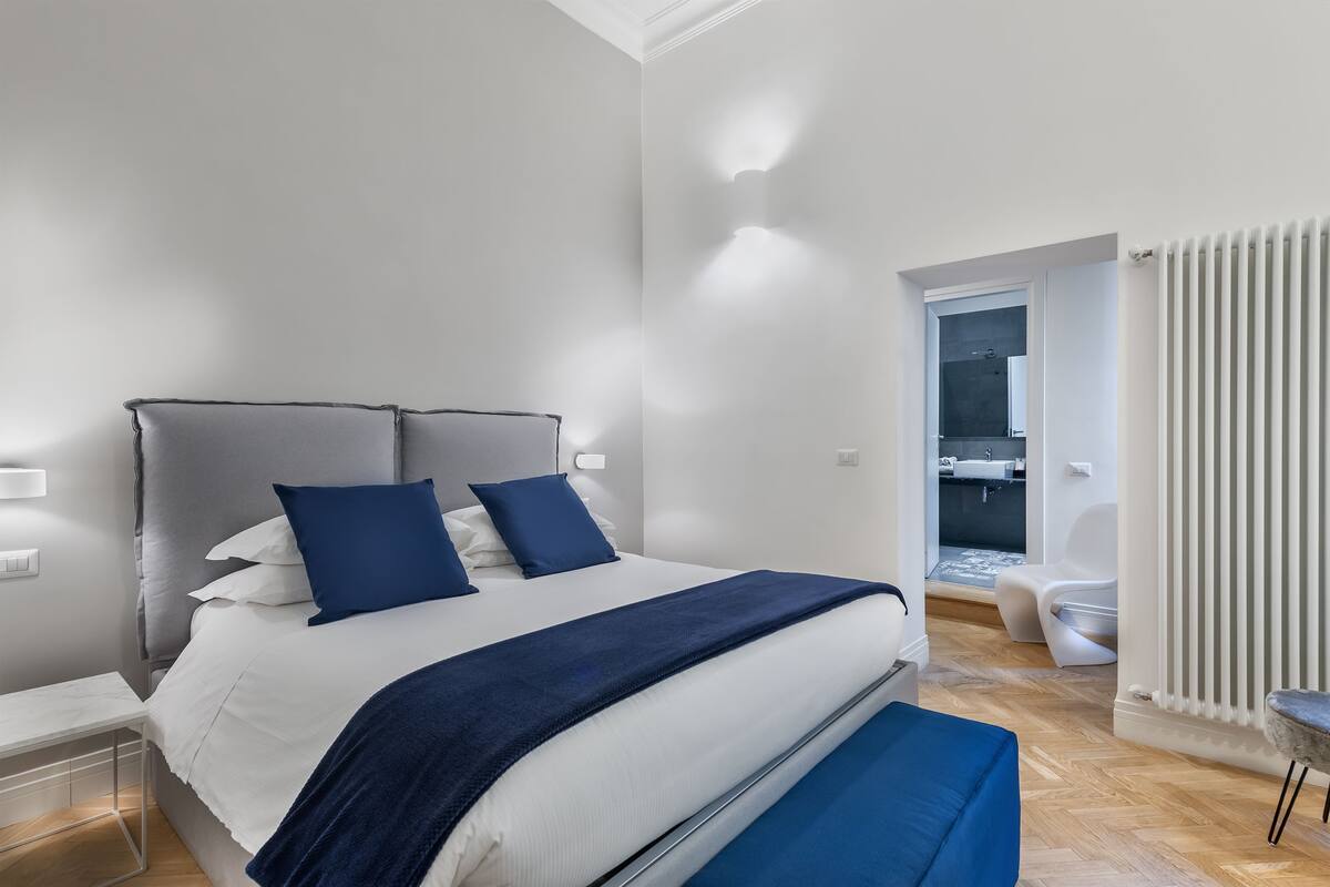 Un dormitorio moderno con una cama grande, una mesita de noche y vistas al baño.