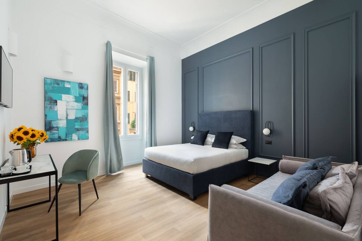 Un dormitorio moderno con cama, sofá, escritorio y un cuadro.