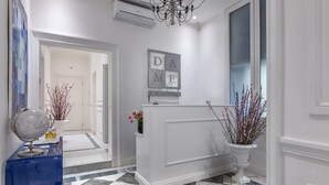 A hallway with a checkered floor, a reception desk, a globe on a blue stand, and a wall-mounted sign. - Da Me Suites (Rome)
