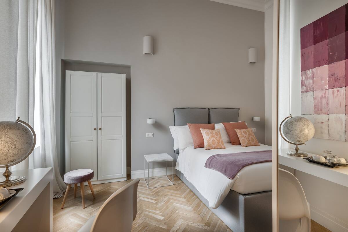 Un dormitorio moderno con una cama, mesitas de noche, un globo terráqueo y un suelo con estampado de espiga.