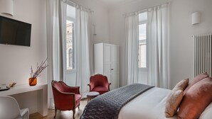 A hotel room with a bed, a desk, a TV, and a view of the city. - Da Me Suites (Rome)