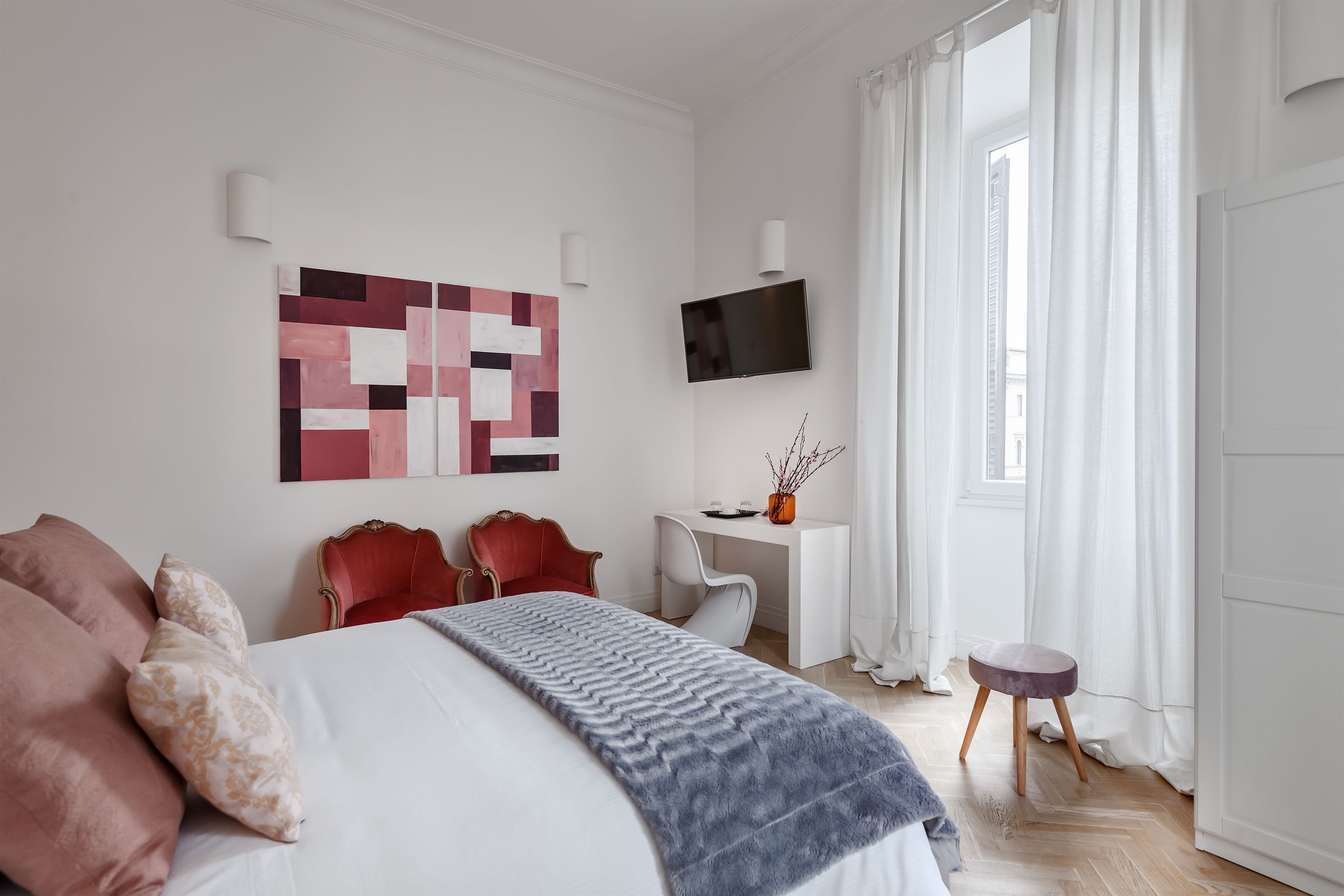 Et moderne hotelværelse med en stor seng, et skrivebord, et fjernsyn og udsigt over byen.