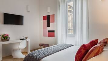 Une chambre d’hôtel moderne dotée d’une télévision à écran plat, d’un bureau avec une chaise, d’un lit agrémenté d’oreillers décoratifs et d’une grande fenêtre avec des rideaux.