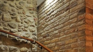 Een trap met een stenen muur aan de ene kant en een bakstenen muur aan de andere kant, met een leuning en een lamp erboven.