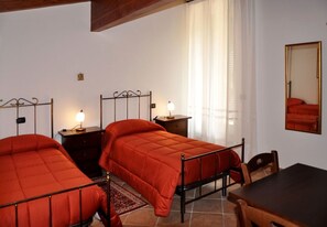 A bedroom with two beds, a wooden table, and a mirror. - B&B Antica Interamnia (Teramo)