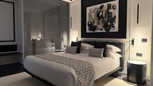 Un dormitorio moderno con una cama grande, un armario de vidrio y un cuadro abstracto contemporáneo.