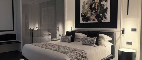 A modern bedroom with a large bed, a glass wardrobe, and a contemporary abstract painting.