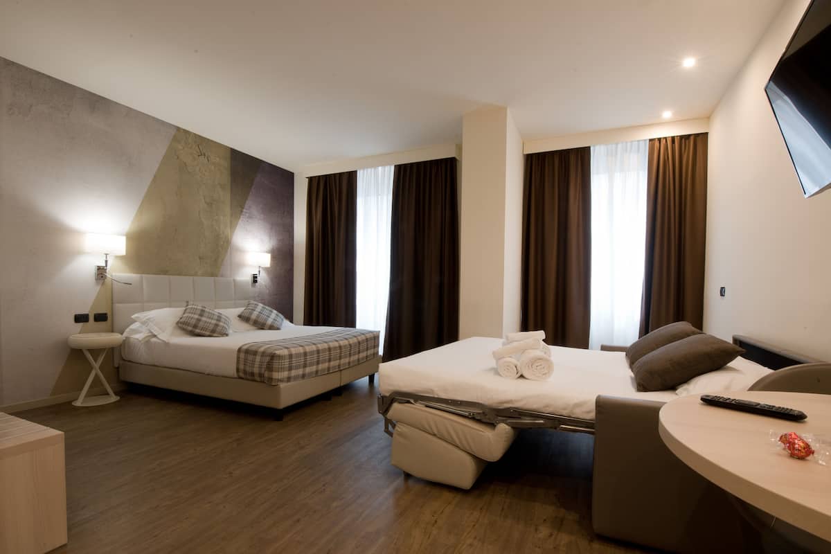 A modern hotel room with two beds, a desk, and a TV.