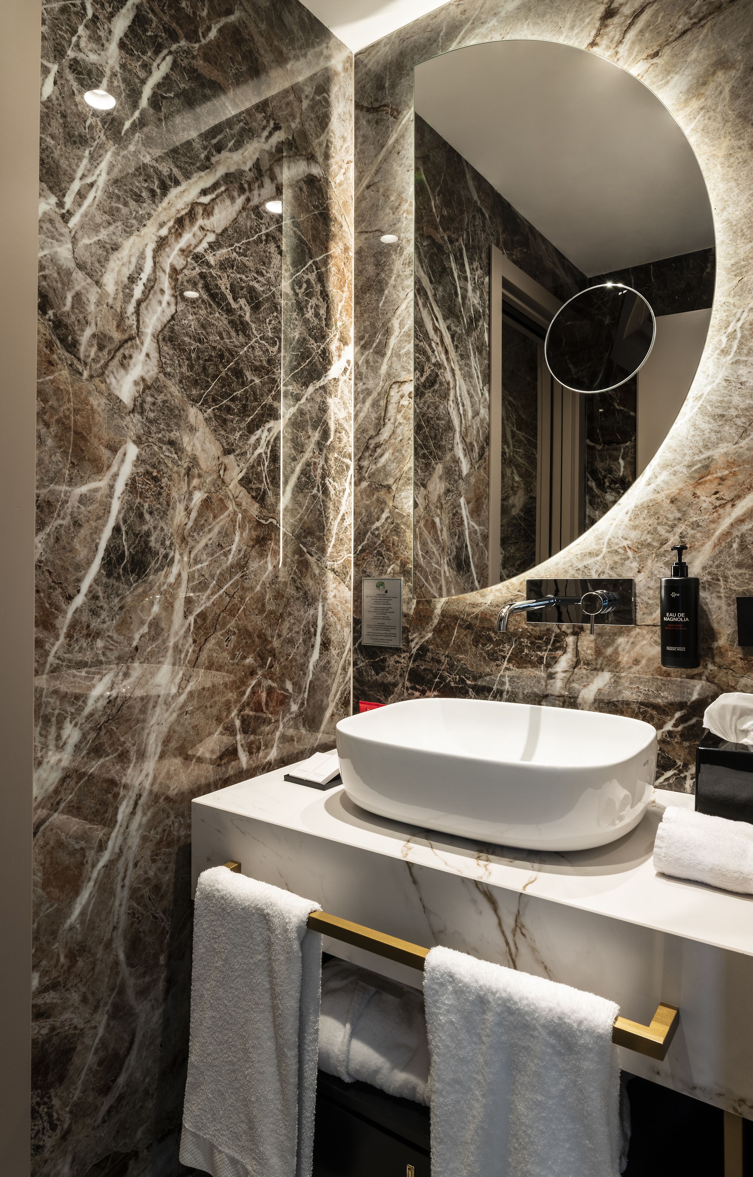 A modern bathroom with a marble vanity, a large mirror, and a sink.