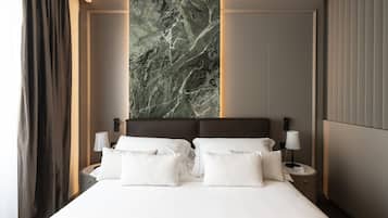 A hotel room with a large bed, two bedside tables with lamps, a marble wall, and a curtain.