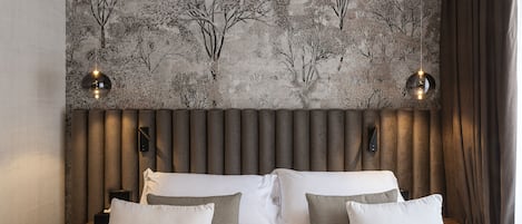 Quarto com uma cama grande, duas mesas de cabeceira, cabeceira com ripas verticais e um mural de árvores na parede.