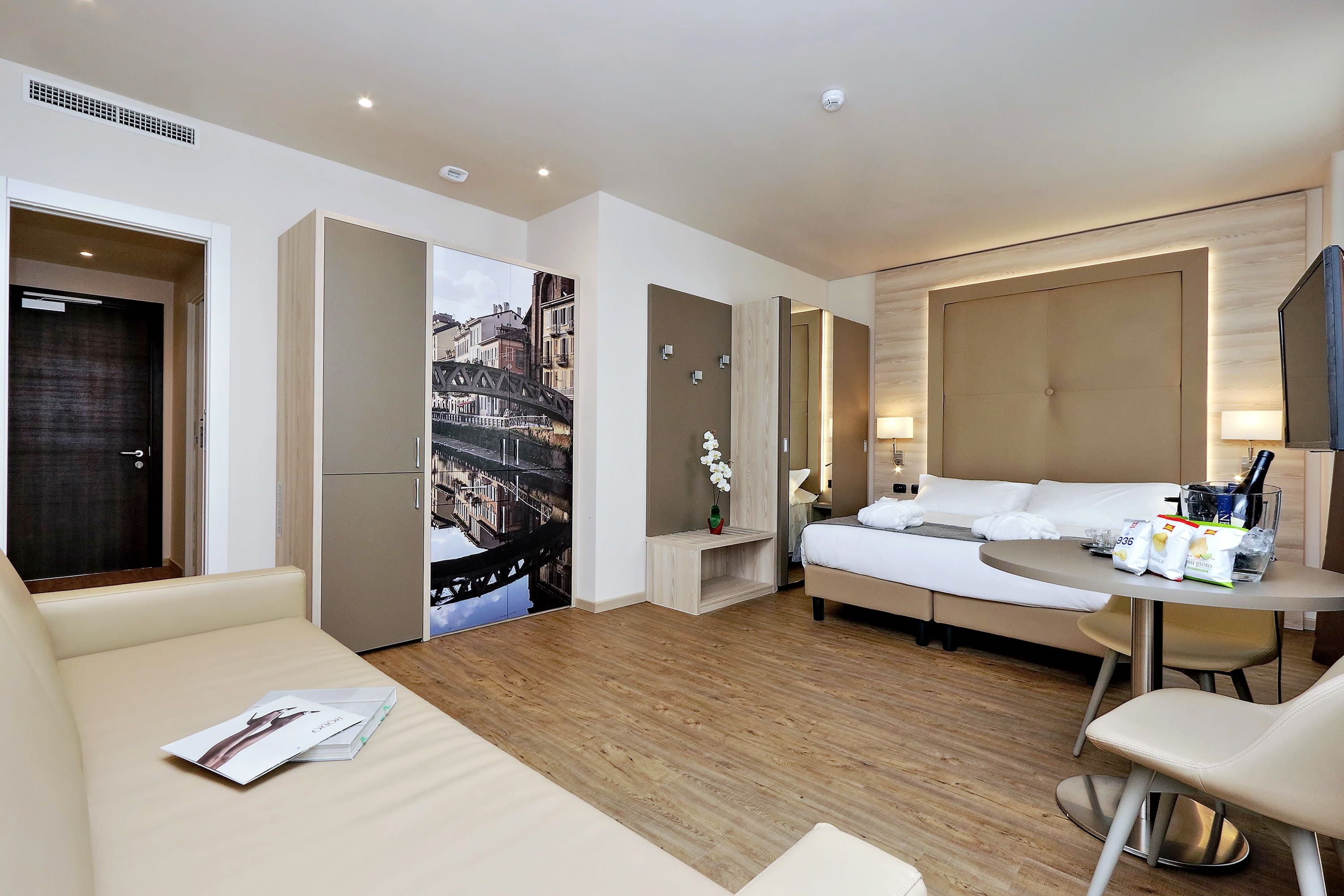 Una moderna camera d'albergo con un letto, una poltrona, un tavolino e una scrivania.