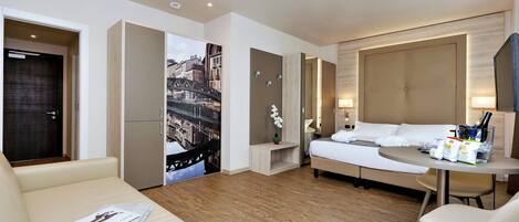 Una habitación de hotel moderna con una cama, un sofá, una mesita y un escritorio.