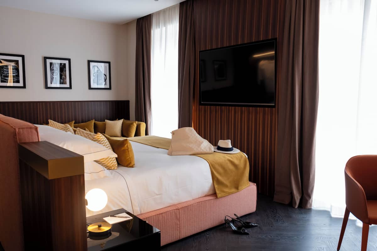 A modern hotel room with a large bed, a flat-screen TV, and framed artwork on the wall.
