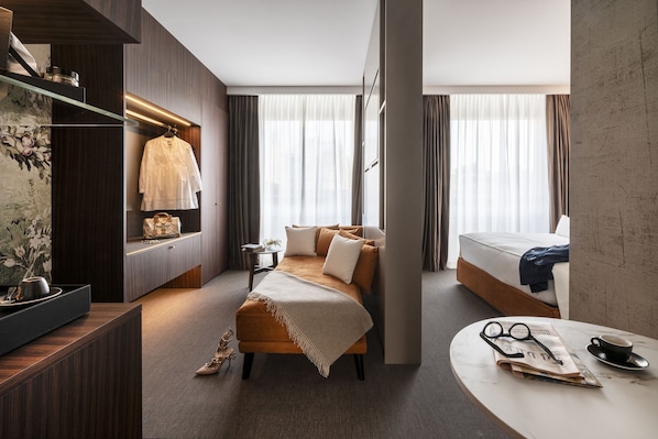 A modern hotel room with a sofa, a bed, a small table with glasses and a cup, and a decorative item on the wall. - Duomo Hotel & Apartments (Milan)