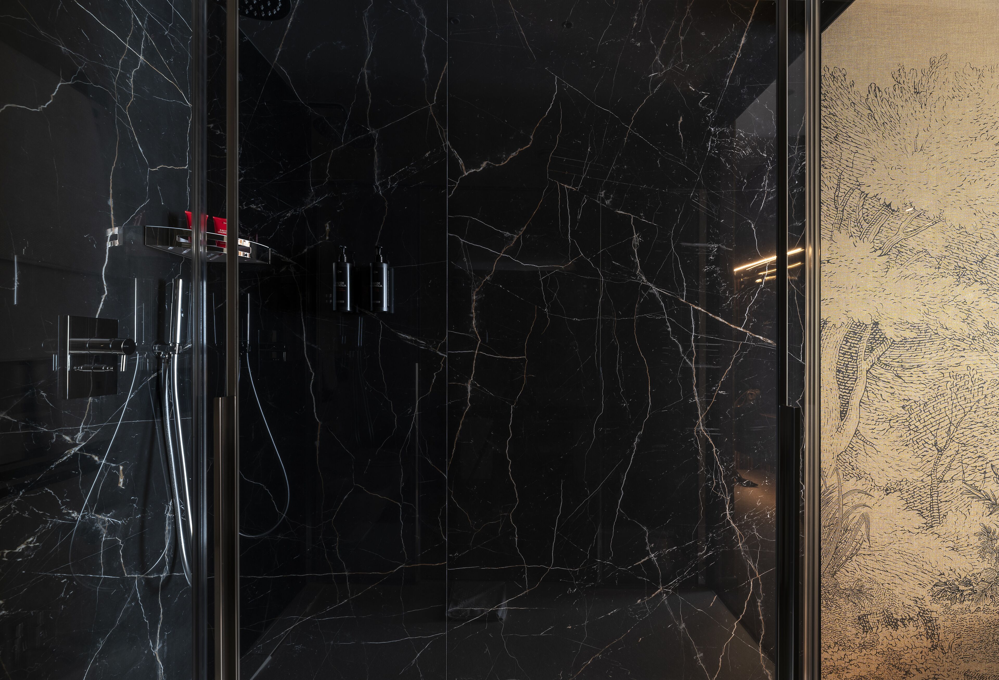 A bathroom with a black marble wall, a glass shower enclosure, and a decorative wall panel.