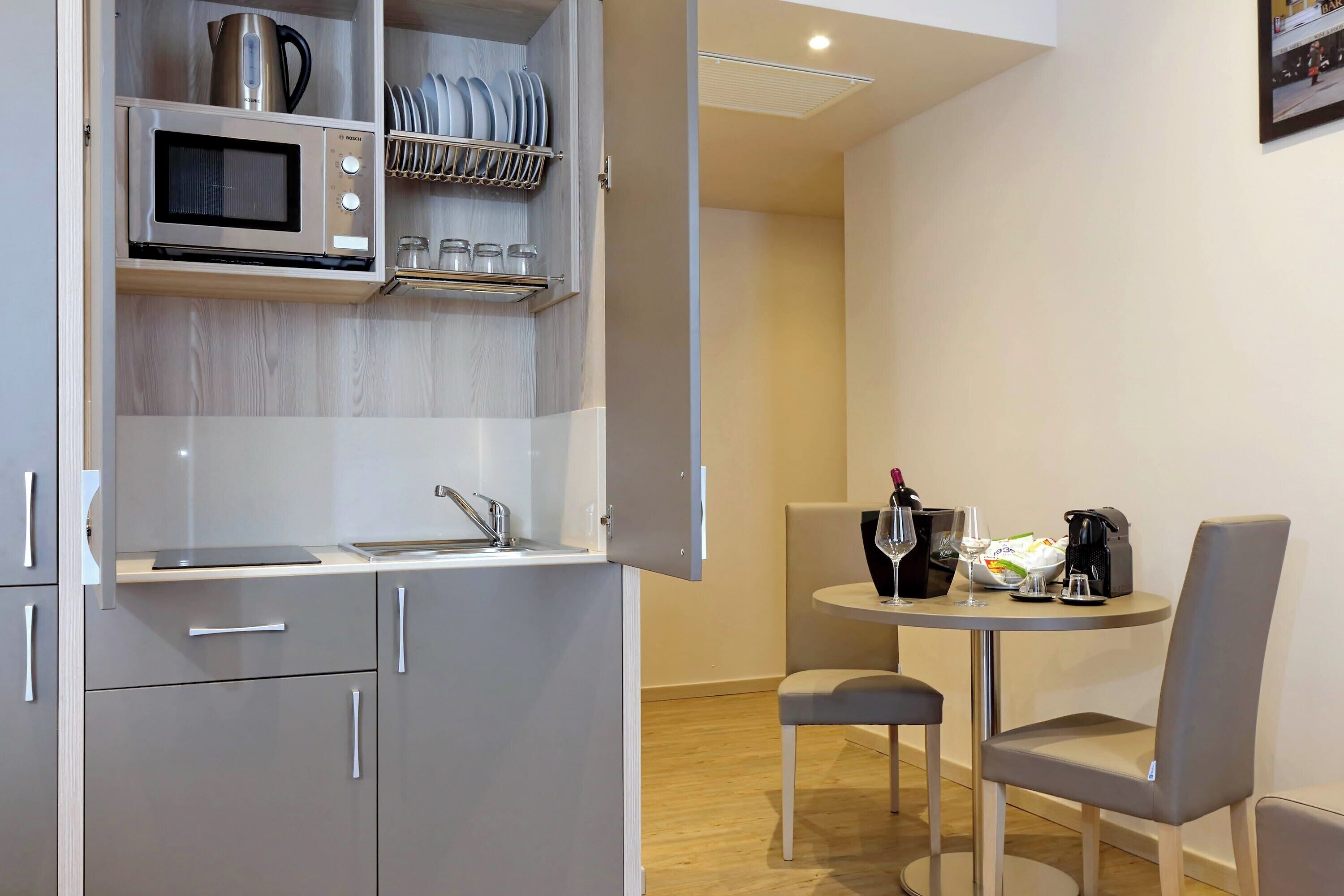 A compact kitchenette with a microwave, sink, and storage shelves.