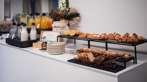 Un bufé con diversos pasteles, bebidas y una decoración floral.