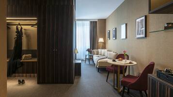 Une chambre d’hôtel comprenant un lit, un coin salon avec une table et des chaises, une armoire et un miroir.