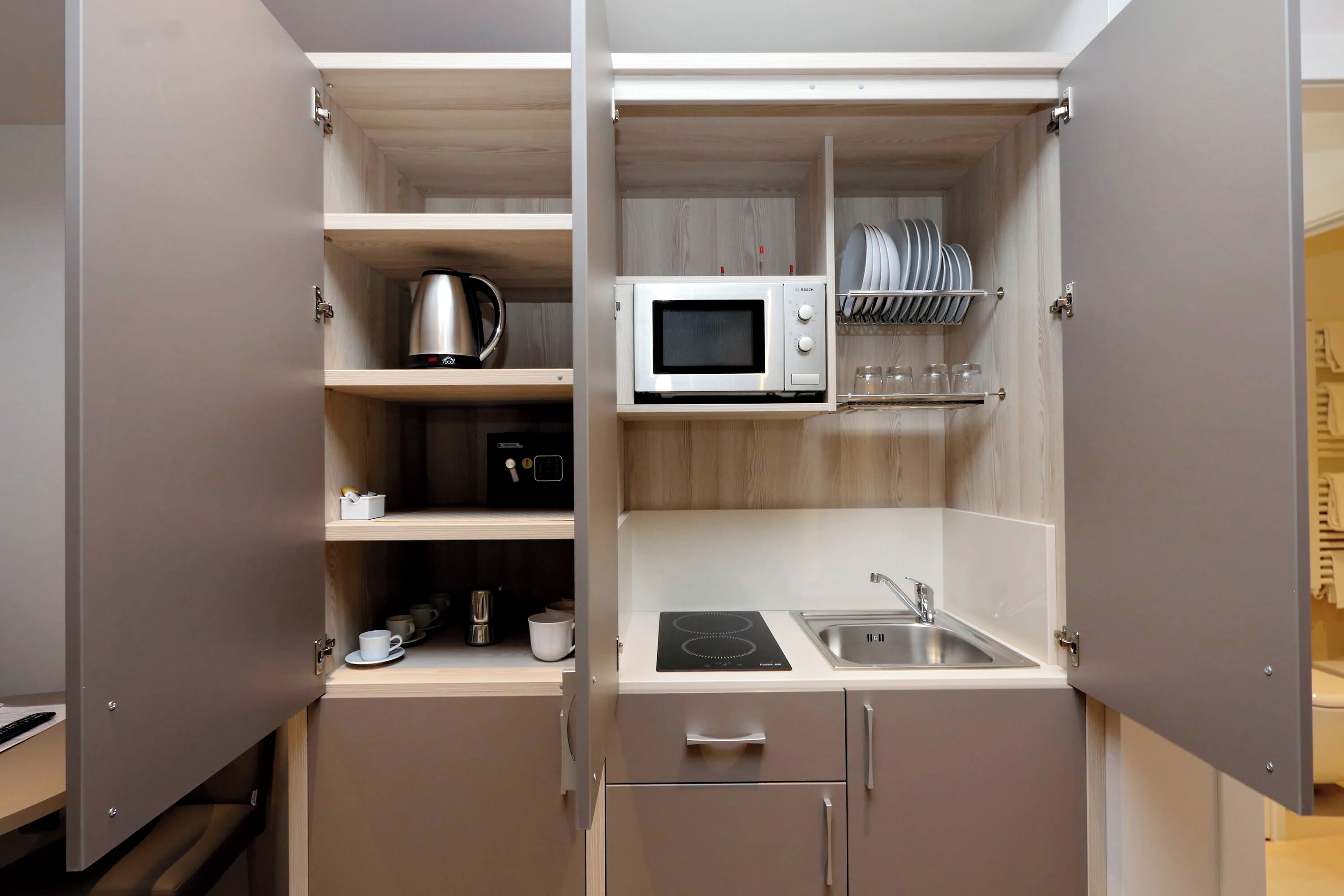 A compact kitchenette with a microwave, kettle, and a small sink.