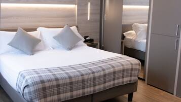 A modern bedroom with a large bed, bedside tables, a wardrobe, and built-in lighting.