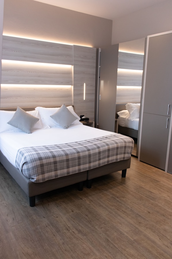 Un dormitorio moderno con una cama grande, mesitas de noche, un armario e iluminación empotrada.