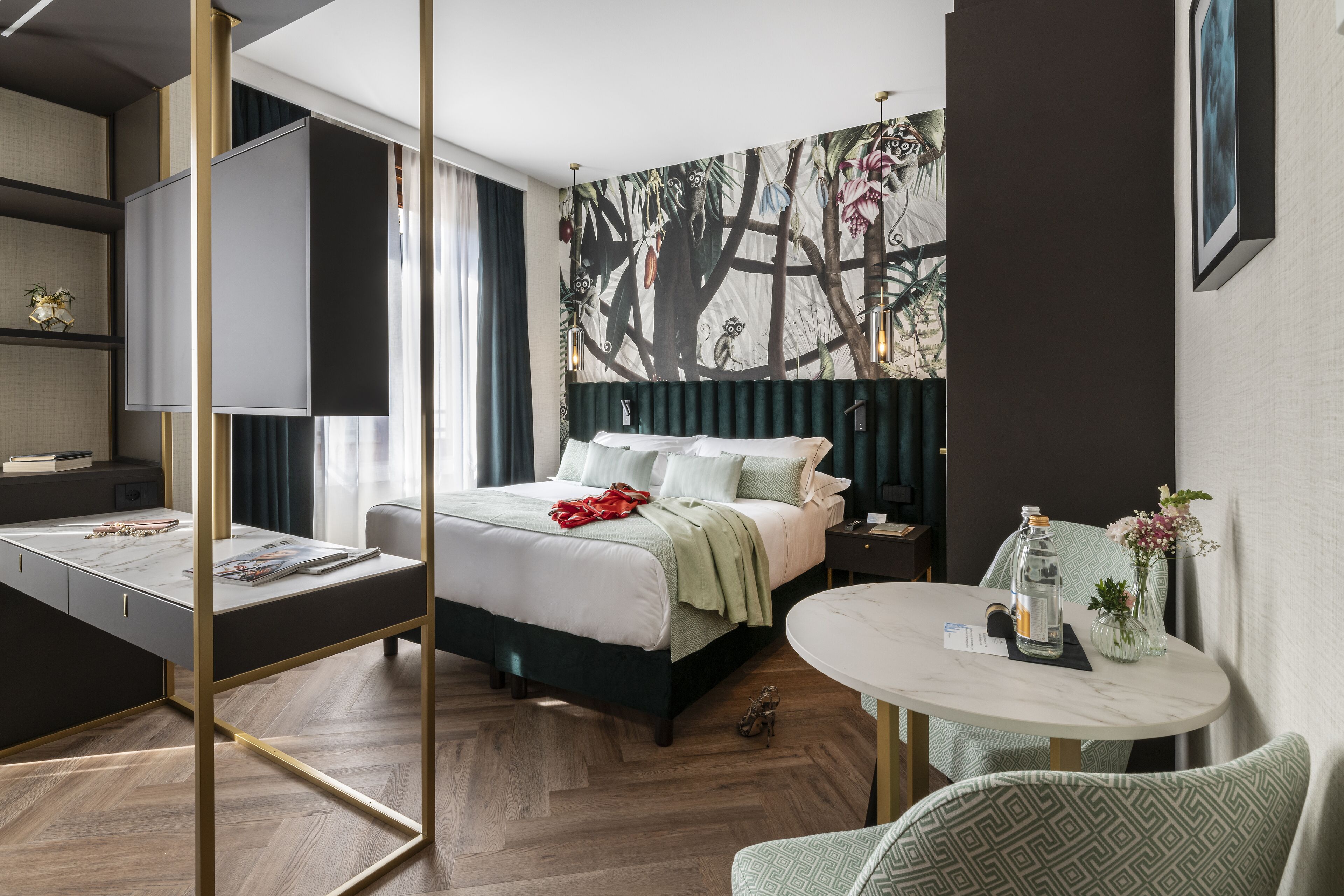 A modern hotel room with a bed, a desk, a round table, and a large wall mural.