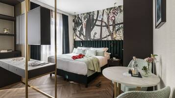 A modern hotel room with a bed, a desk, a round table, and a large wall mural.
