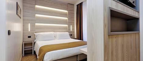 Una habitación de hotel moderna con cama, mesitas de noche, televisor y estante empotrado.