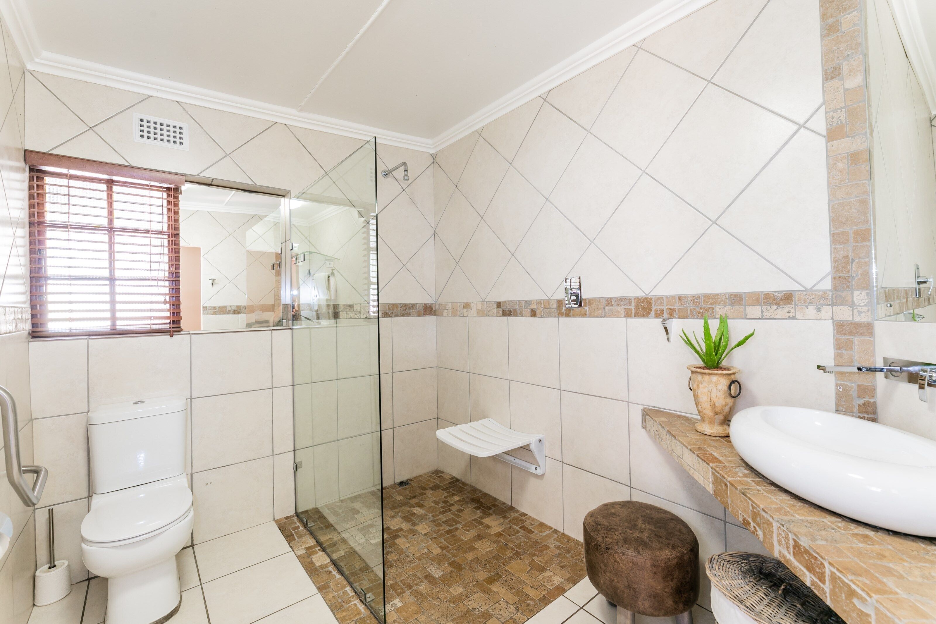 Bagno con WC, doccia, lavandino e una pianta in vaso.