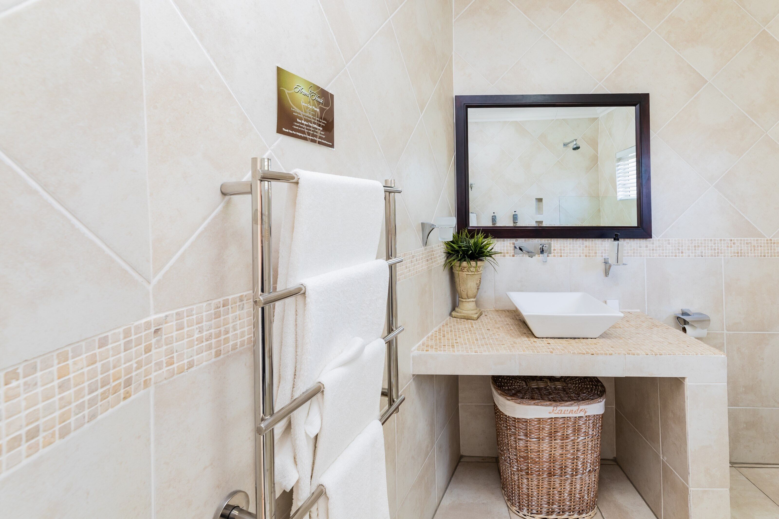Un baño con toallero, lavabo, espejo y cubo de basura.
