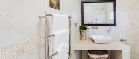 Un baño con toallero, lavabo, espejo y cubo de basura.